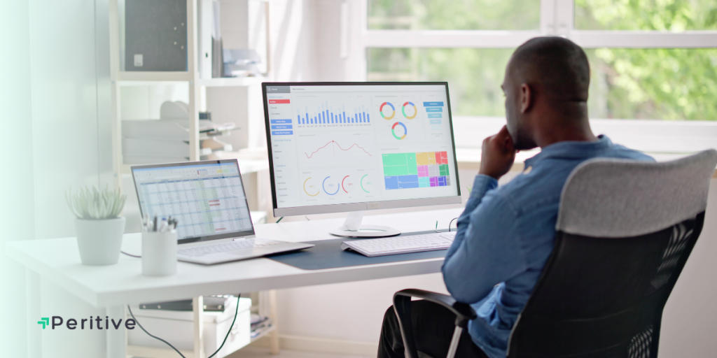 A man in an office analyzing data charts on a computer screen.
